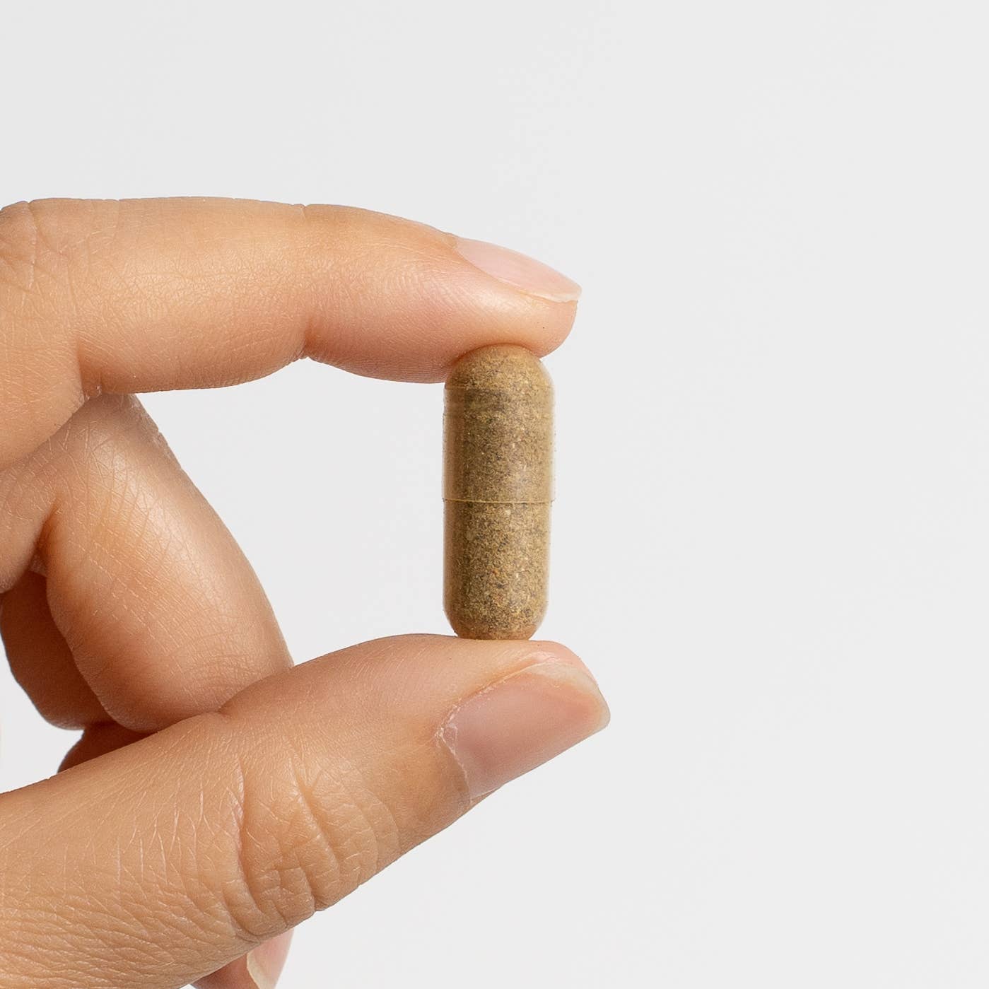 
                  
                    Hand holding a single Food Over Drugs Cystic Acne Formula herbal capsule between finger and thumb
                  
                
