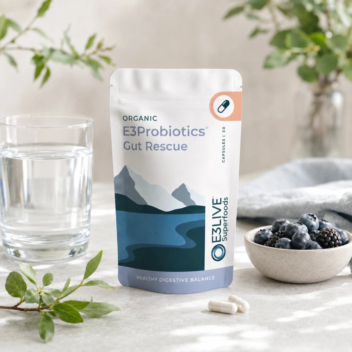 
                  
                    E3Probiotics Gut Rescue pouch on a stone bench beside a glass of water, loose capsules and a bowl of berries
                  
                