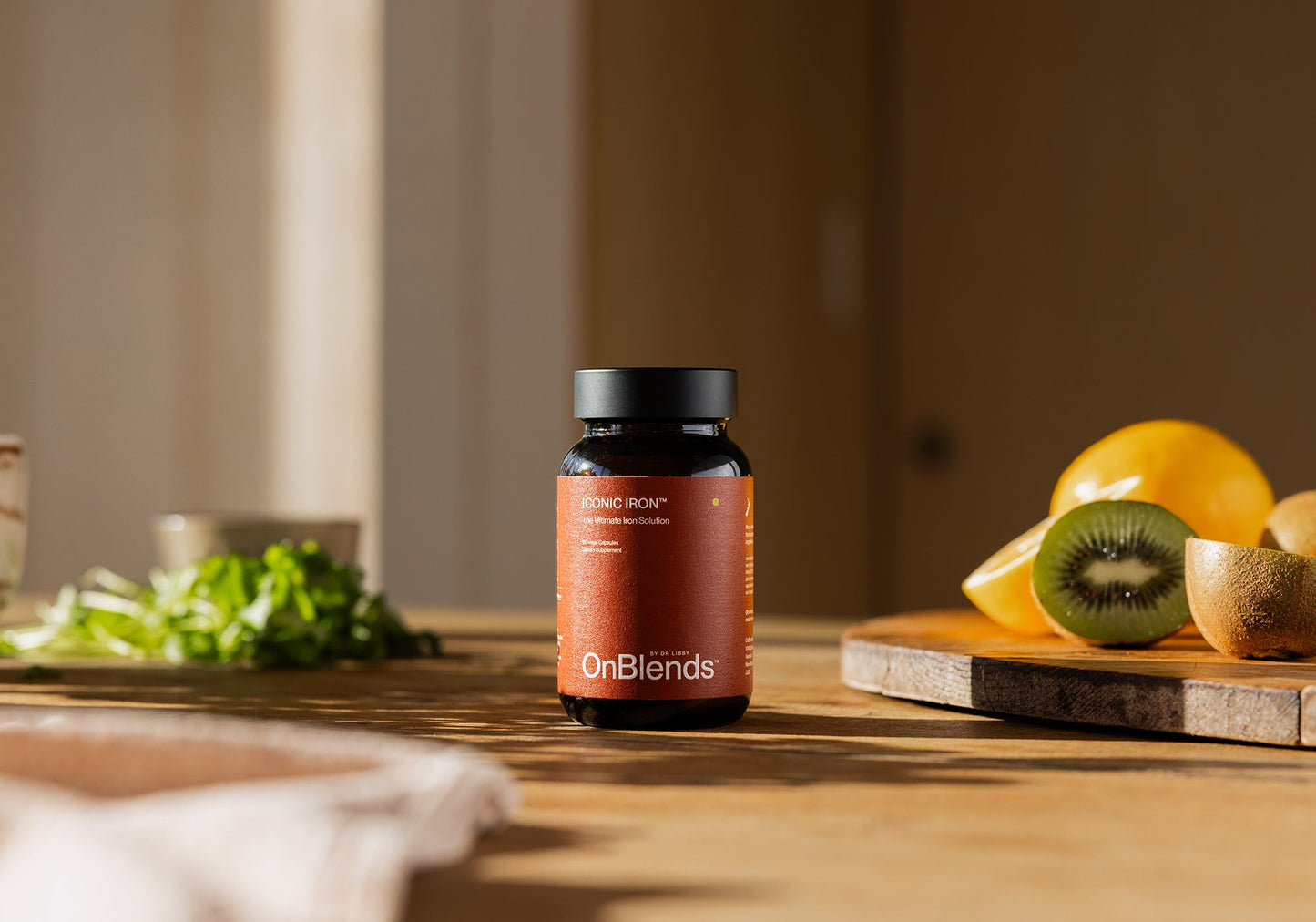 
                  
                    OnBlends Iconic Iron bottle styled on a kitchen bench with greens and citrus
                  
                