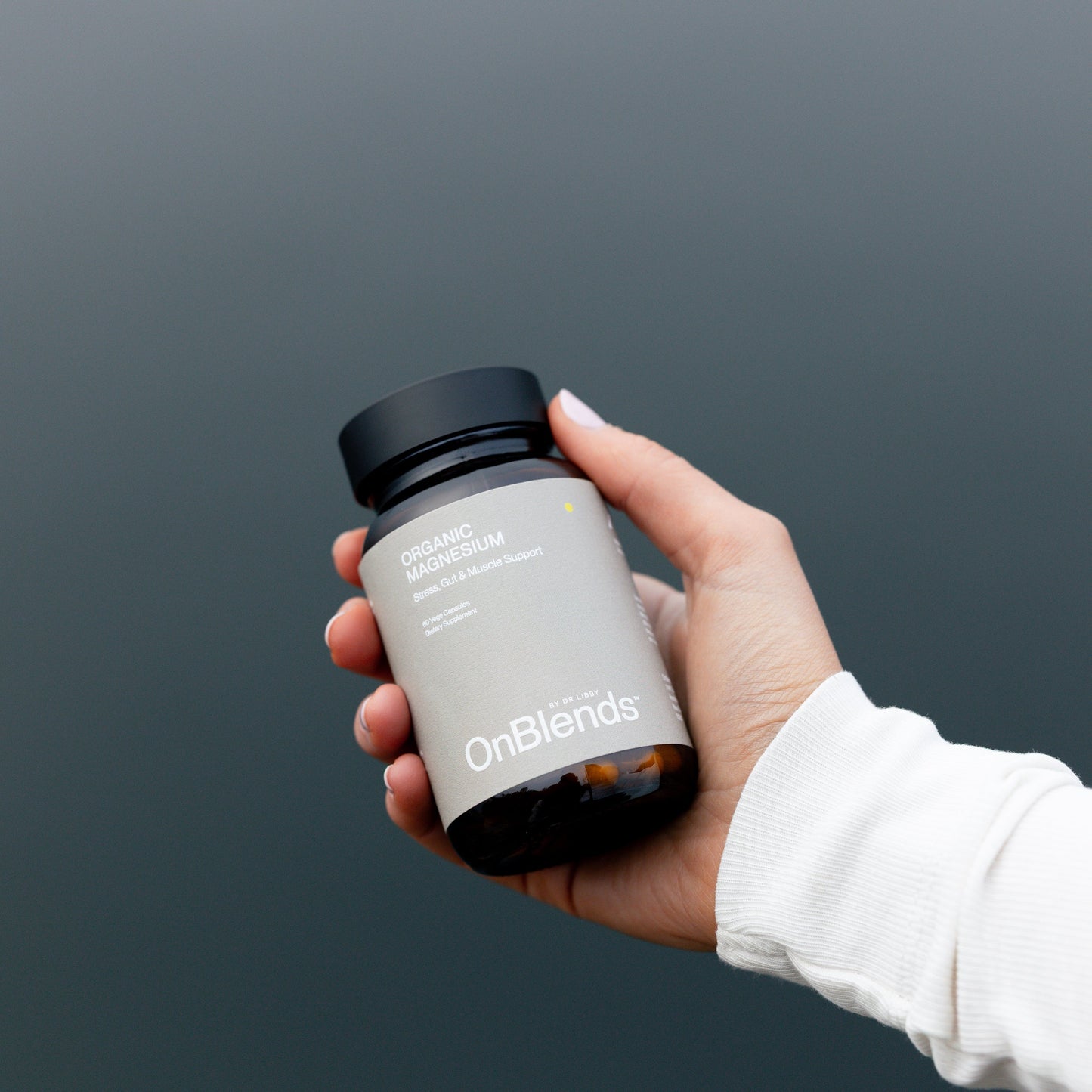 
                  
                    Hand holding the OnBlends Organic Magnesium bottle against a dark grey background
                  
                