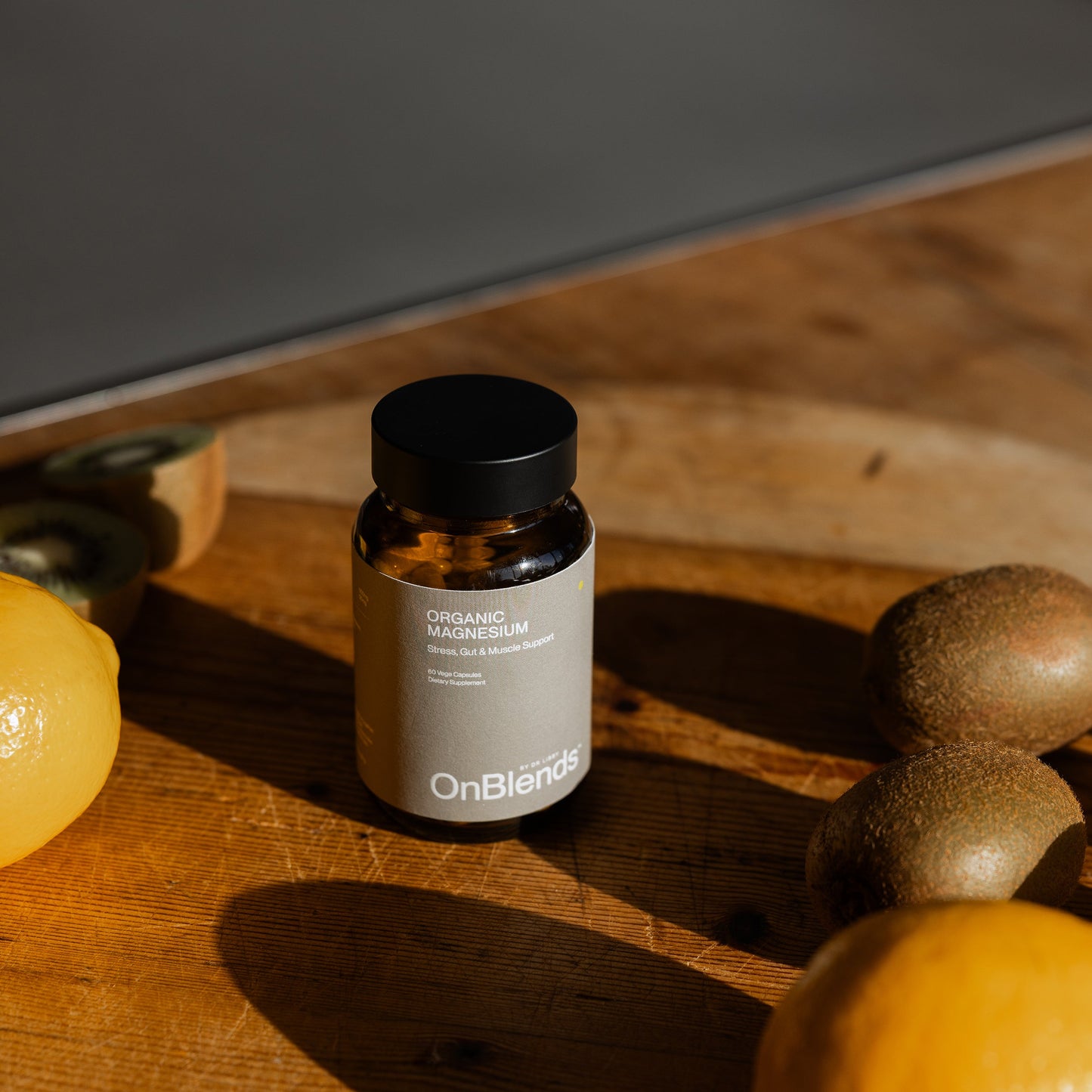 
                  
                    OnBlends Organic Magnesium bottle on a sunlit timber bench beside lemons and halved kiwifruit
                  
                