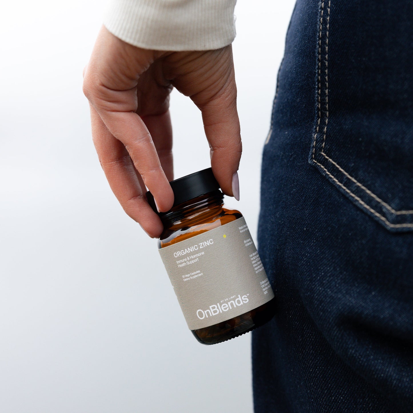 
                  
                    Woman carrying the OnBlends Organic Zinc bottle at her side in denim and cream
                  
                